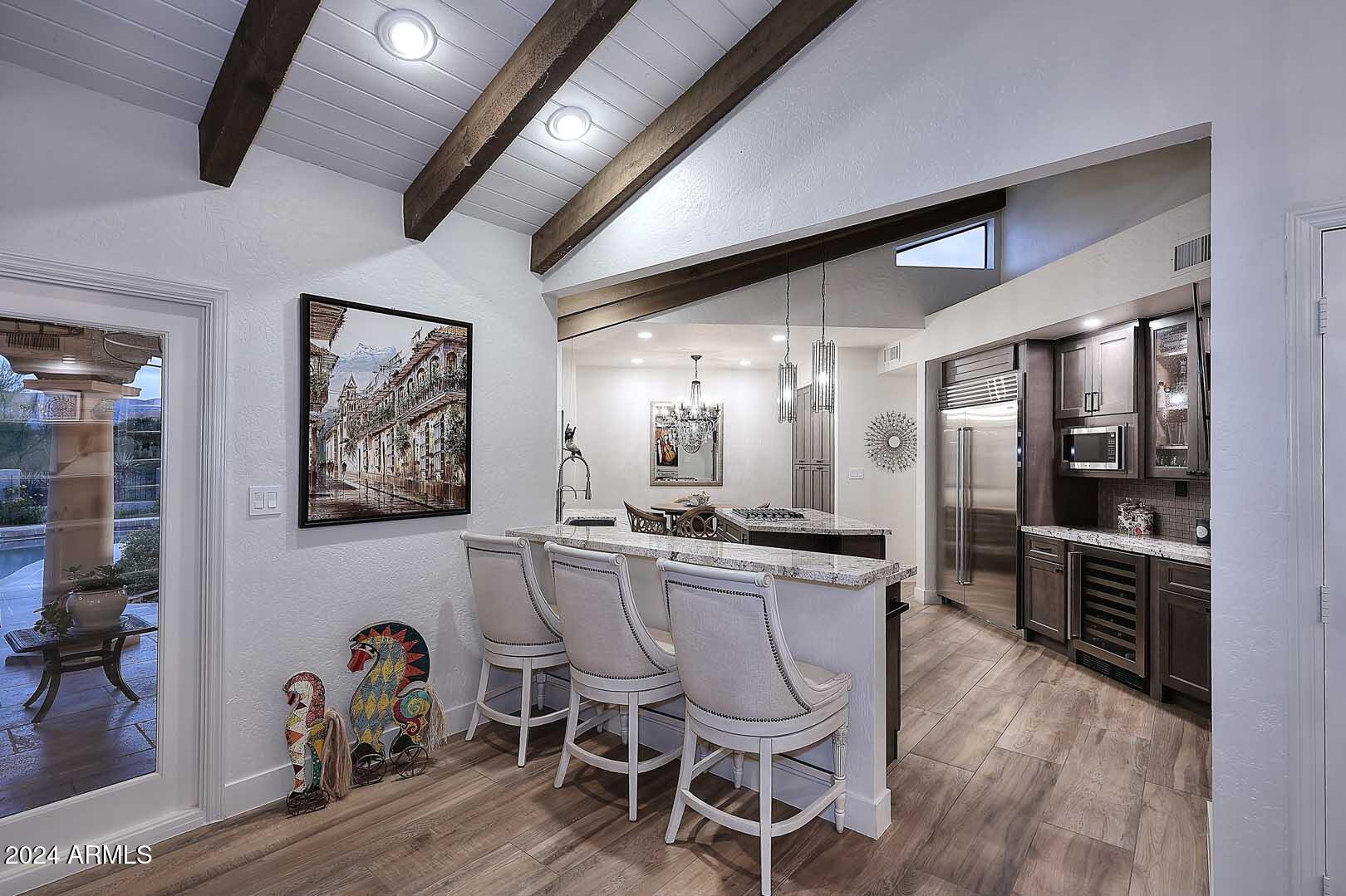 9446 Romping Road Carefree, AZ 85377 - Photo 26 of 119 a kitchen with stainless steel appliances kitchen island granite countertop a table chairs in it and wooden floors