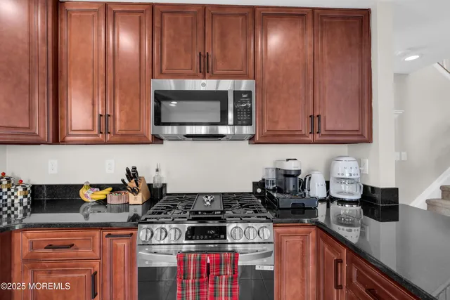 a kitchen with granite countertop a sink a stove and cabinets