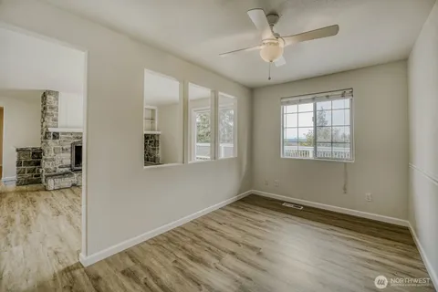 a view of an empty room with wooden floor and a window