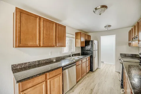a kitchen with granite countertop a sink stove and cabinets