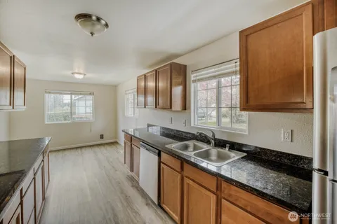a kitchen with stainless steel appliances granite countertop a stove a sink dishwasher and cabinets with wooden floor
