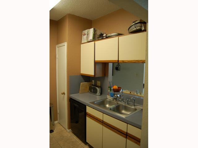 2804 Rio Grande Street, Unit 307 Austin, TX 78705 - Photo 11 of 14 Kitchen with two tone cabinets, black dishwasher, light tile patterned flooring, and a textured ceiling