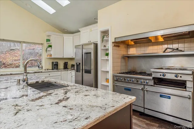a kitchen with granite countertop a stove a sink and a refrigerator