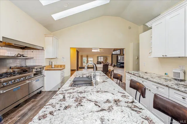 a large kitchen with stainless steel appliances stove a sink dishwasher and cabinets with wooden floor