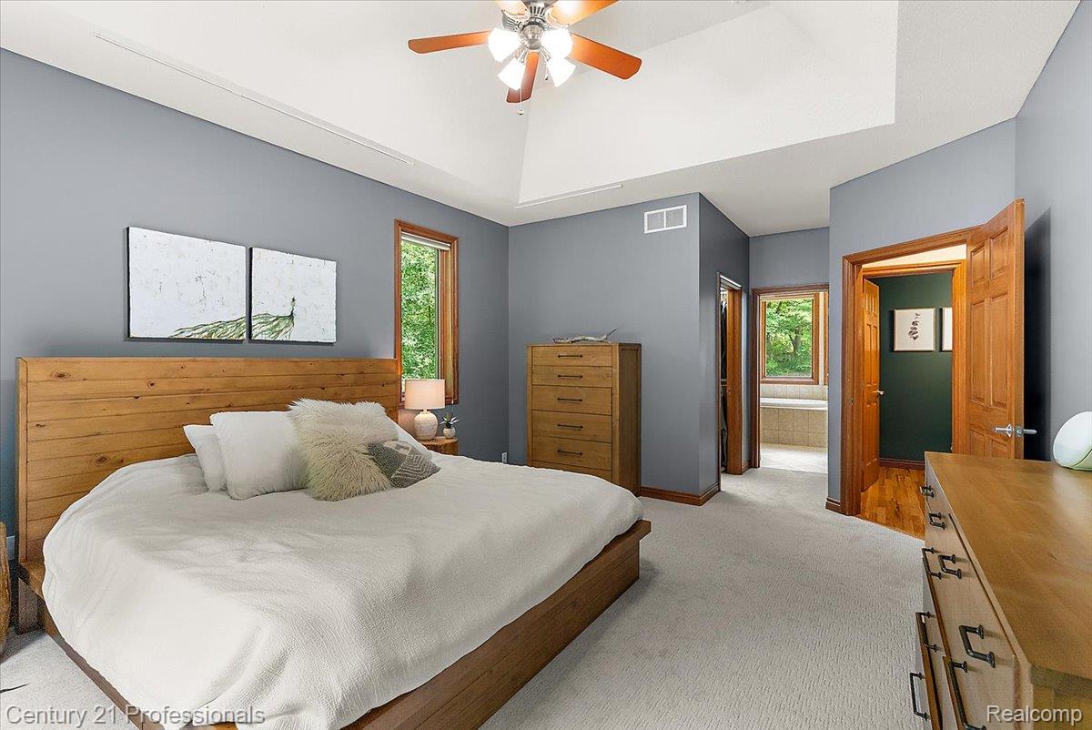 9867 Rainbow Ridge Drive Schoolcraft, MI 49087 - Photo 32 of 82 Spacious bedroom featuring vaulted ceilings, a ceiling fan with integrated lighting, wood-trimmed windows, light-colored carpeting, and a visible doorway leading to a separate area with a built-in tub