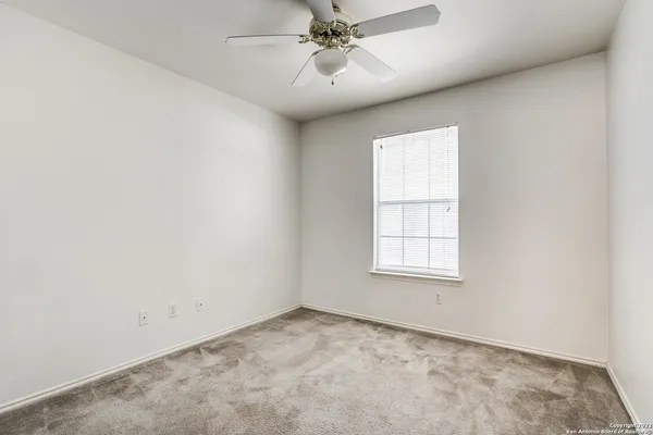 an empty room with a window and a ceiling fan