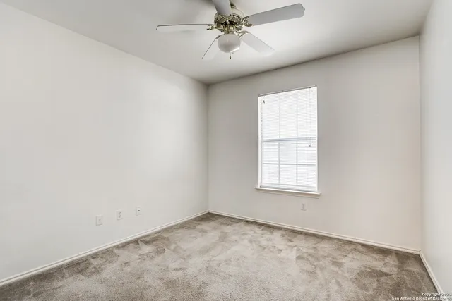 an empty room with a window and a ceiling fan