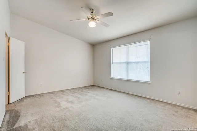 an empty room with windows and ceiling fan