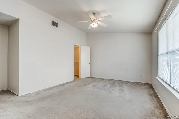 an empty room with windows and ceiling fan