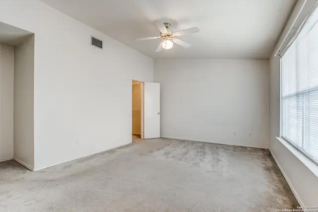 an empty room with windows and ceiling fan