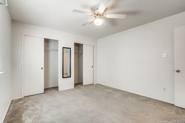 an empty room with a ceiling fan and a window