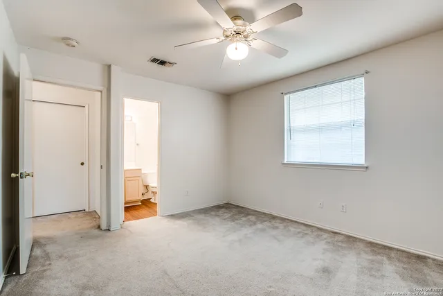 an empty room with a ceiling fan and a window