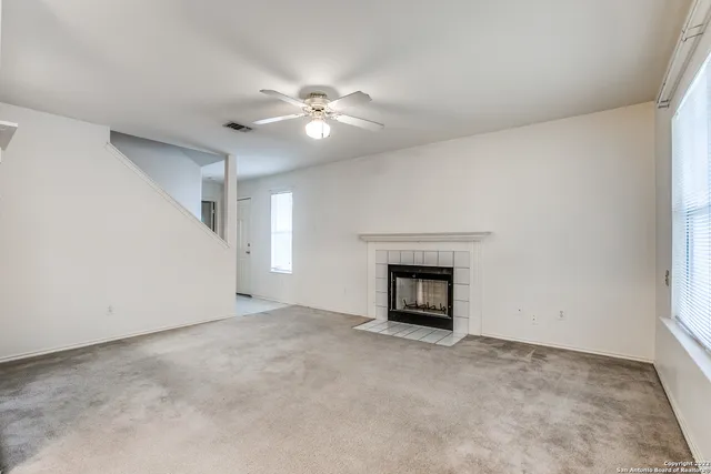an empty room with a fireplace and a ceiling fan