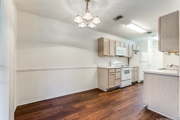 a kitchen with stainless steel appliances granite countertop a refrigerator a sink dishwasher a stove and white countertops with wooden floor