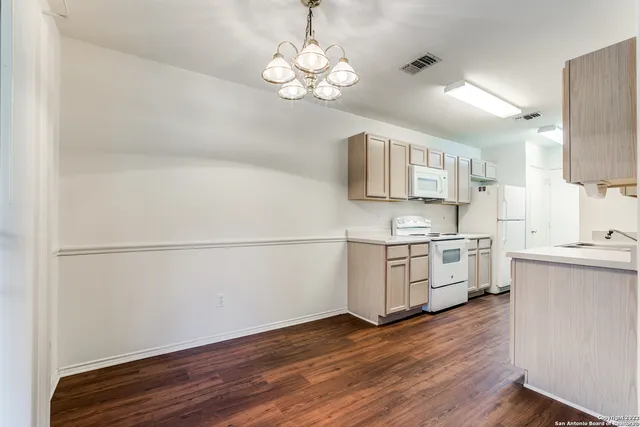 a kitchen with stainless steel appliances granite countertop a refrigerator a sink dishwasher a stove and white countertops with wooden floor