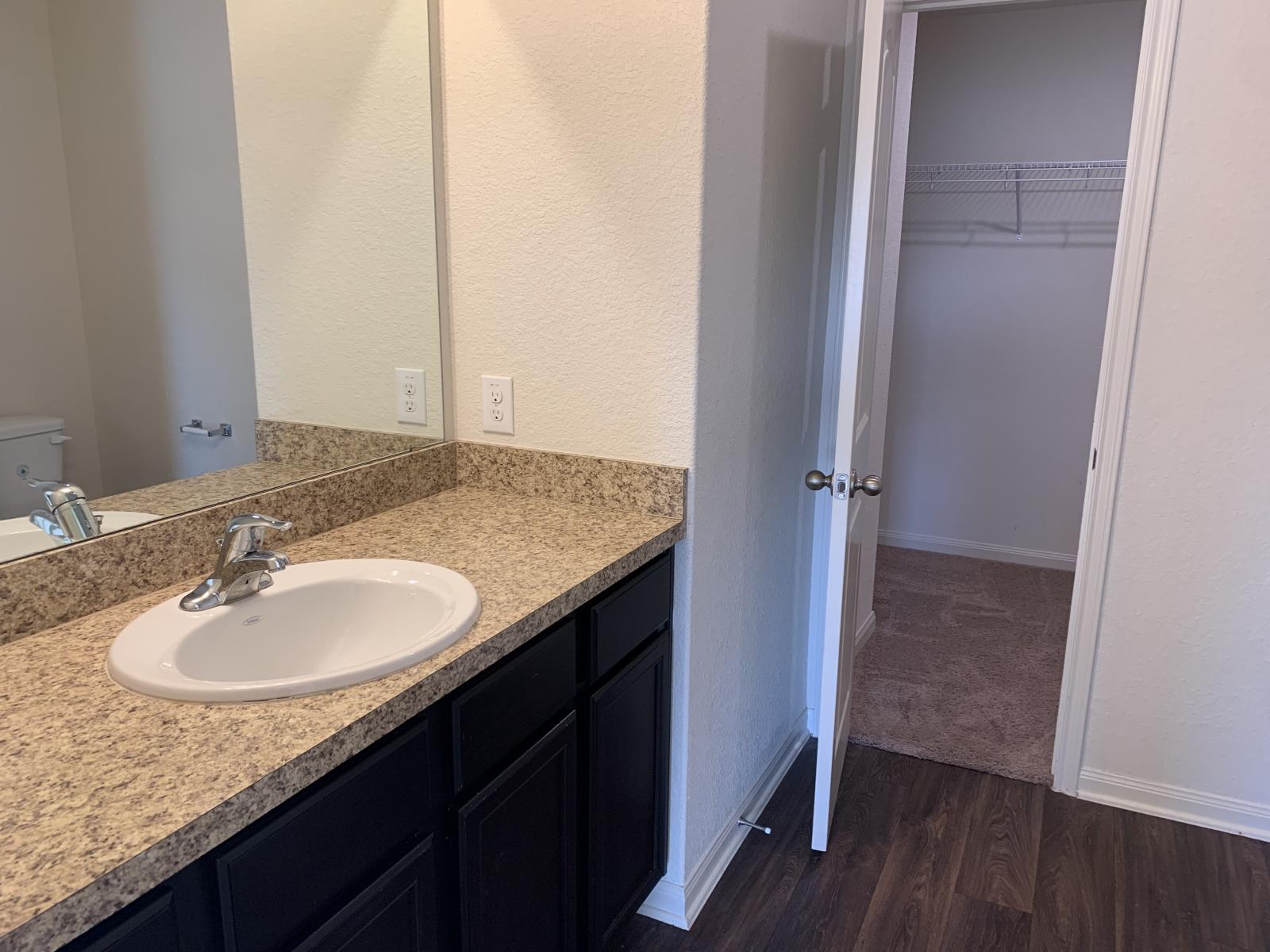 217 Denson Lane Jarrell, TX 76537 - Photo 15 of 26 Bathroom vanity featuring a light speckled countertop, undermount sink with chrome faucet, and dark wood-finish cabinetry
