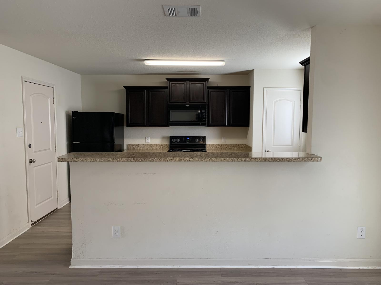 217 Denson Lane Jarrell, TX 76537 - Photo 22 of 26 Kitchen featuring dark wood-finish cabinetry, granite-style countertops, and a breakfast bar