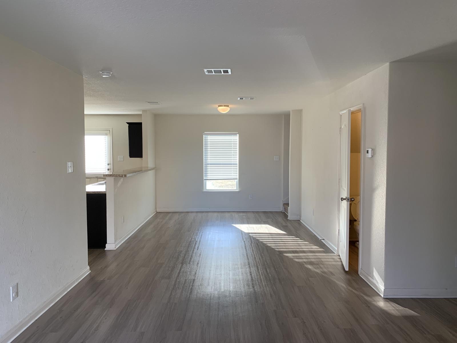 217 Denson Lane Jarrell, TX 76537 - Photo 23 of 26 Open-concept living space featuring wood-finish flooring, neutral wall tones, and a window with blinds