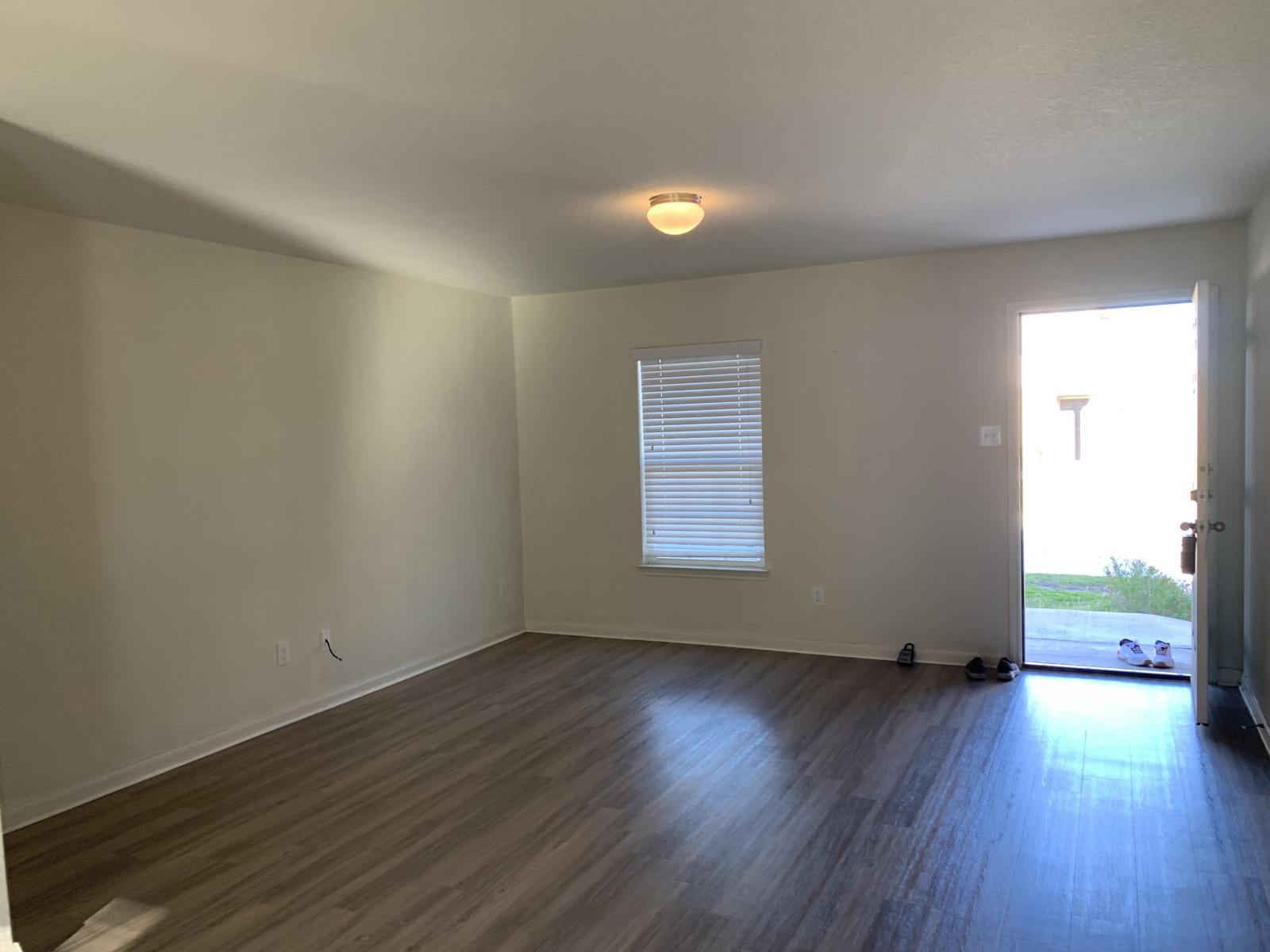 217 Denson Lane Jarrell, TX 76537 - Photo 25 of 26 Spacious room featuring wood-finish flooring, a neutral color palette, a window with horizontal blinds, and an overhead flush-mount light fixture