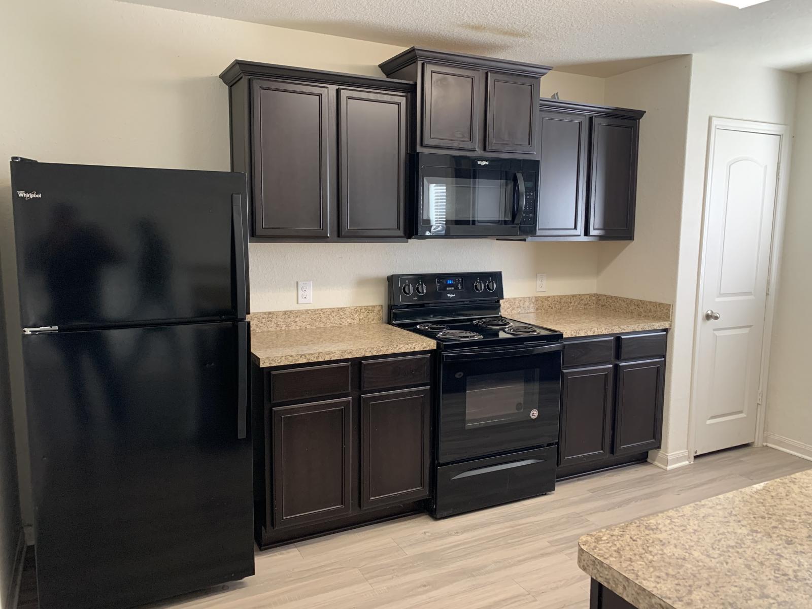 217 Denson Lane Jarrell, TX 76537 - Photo 26 of 26 Kitchen featuring dark wood-finish cabinetry, light-toned countertops, and black appliances