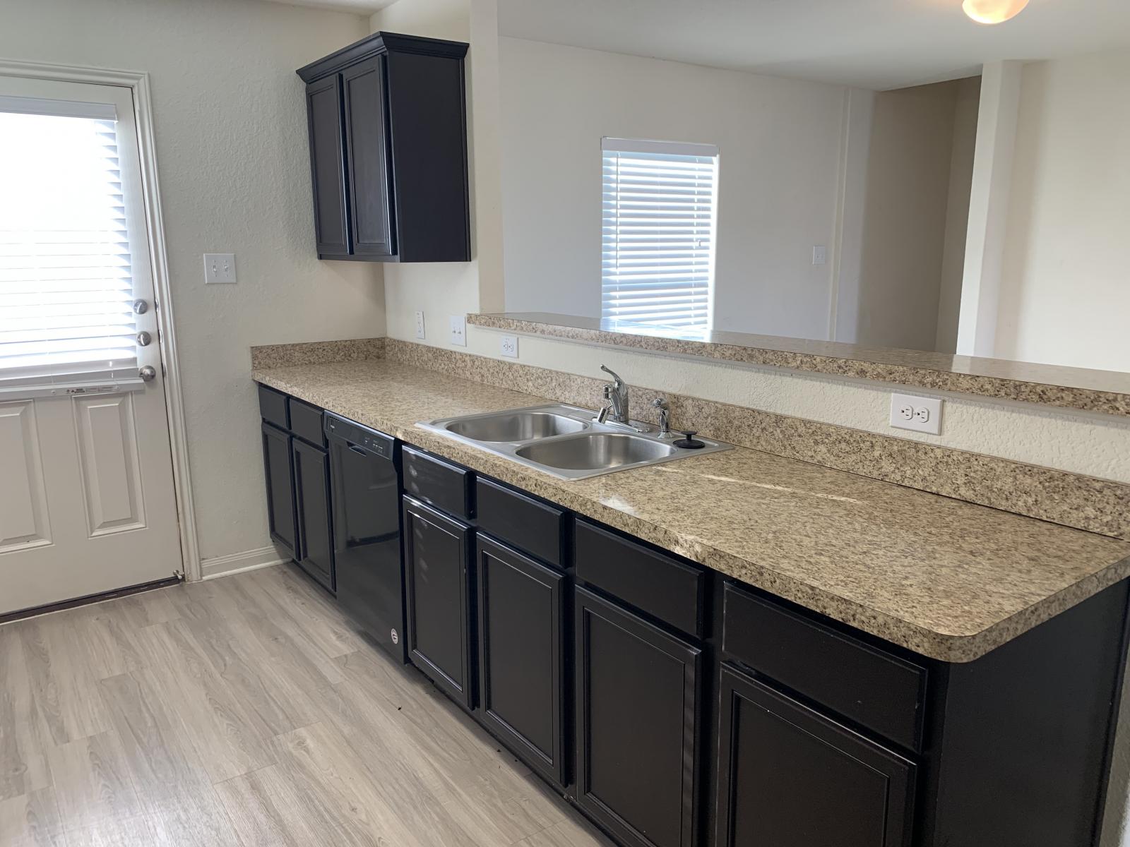 217 Denson Lane Jarrell, TX 76537 - Photo 5 of 26 Kitchen featuring dark cabinetry, light-toned countertops, a double basin sink, and wood-finish flooring