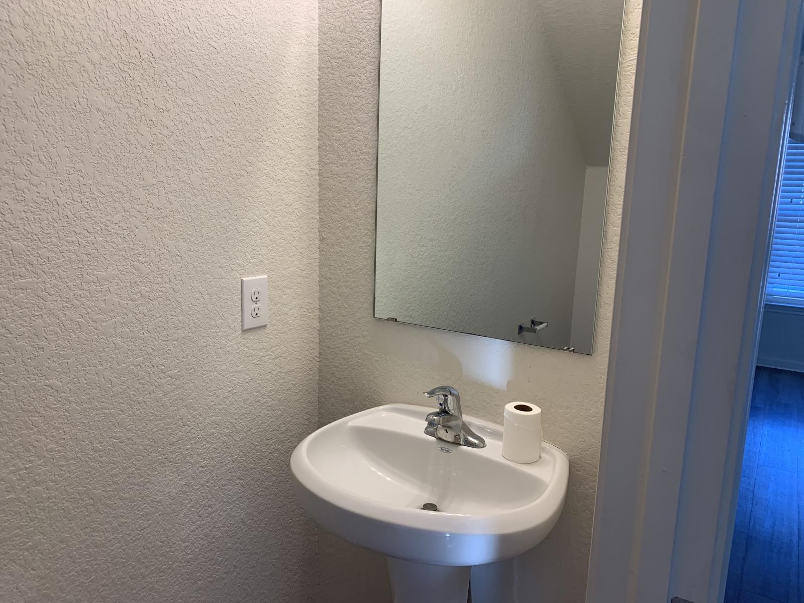 217 Denson Lane Jarrell, TX 76537 - Photo 10 of 26 Pedestal sink with a chrome faucet and a wall-mounted mirror