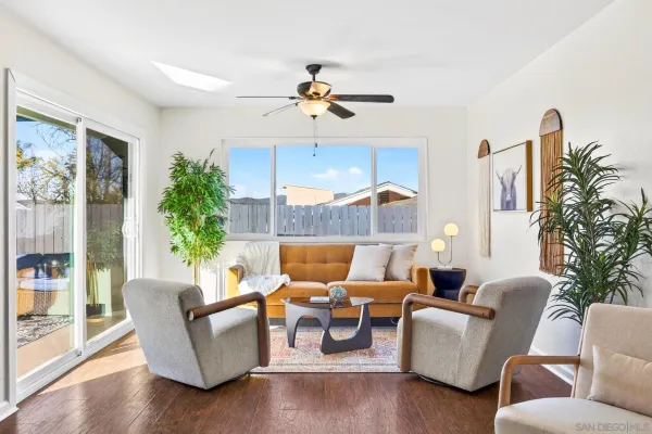 a living room with furniture ceiling fan and a large window