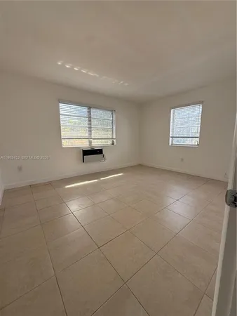 an empty room with windows and fireplace