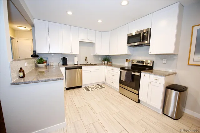a kitchen with white cabinets sink and stainless steel appliances