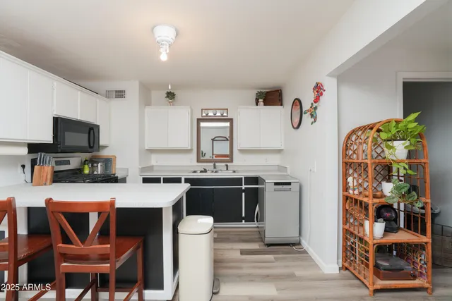 a kitchen with stainless steel appliances granite countertop a stove a sink dishwasher and a refrigerator with wooden floor