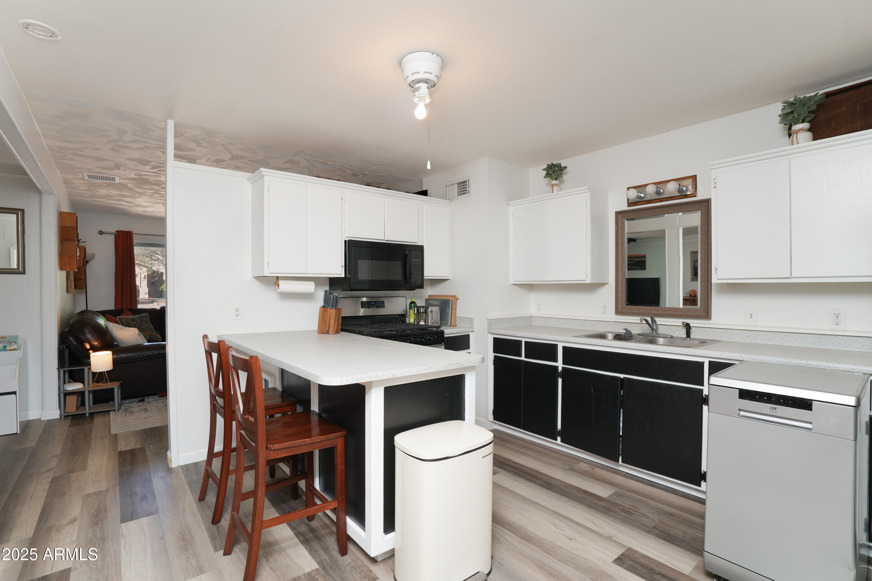 605 3rd N Street Clarkdale, AZ 86324 - Photo 13 of 37 a kitchen with stainless steel appliances a stove top oven a sink dishwasher and a refrigerator with wooden floor