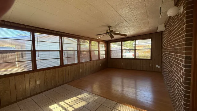an empty room with wooden floor and chandelier fan