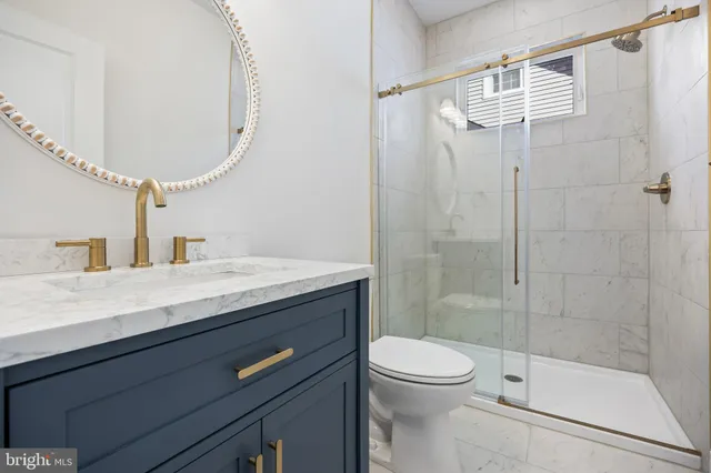 a bathroom with a granite countertop sink a toilet and shower