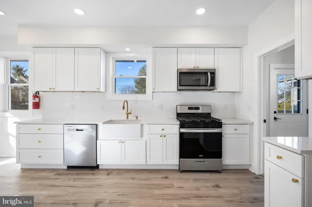 a kitchen with cabinets stainless steel appliances and wooden floor