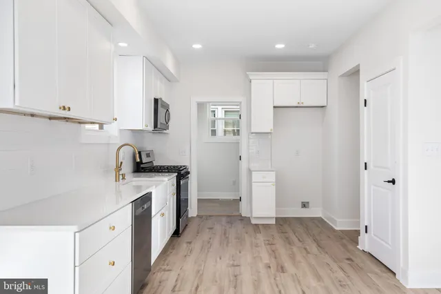 a kitchen with a refrigerator a sink and wooden floor