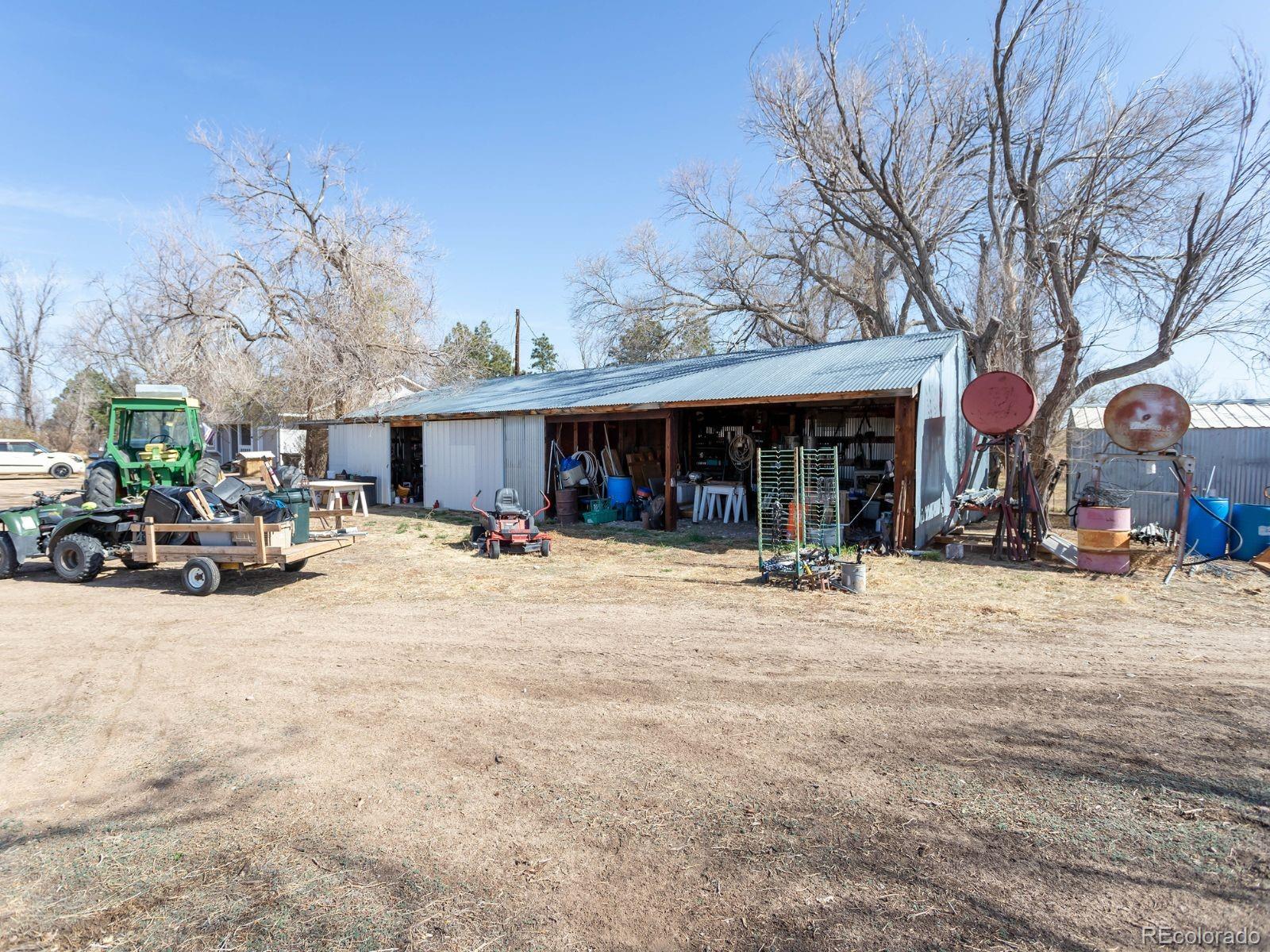 6115 Sengbeil Road Yoder, CO 80864 - Photo 31 of 43 a view of a house with a barbeque and large trees