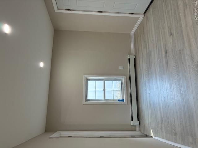 Unfurnished room with light wood-style floors, baseboard heating, and recessed lighting