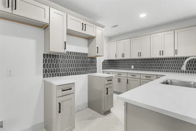 a kitchen with white cabinets sink and stove