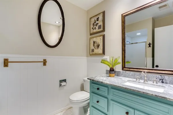 a bathroom with a granite countertop toilet a sink and a mirror