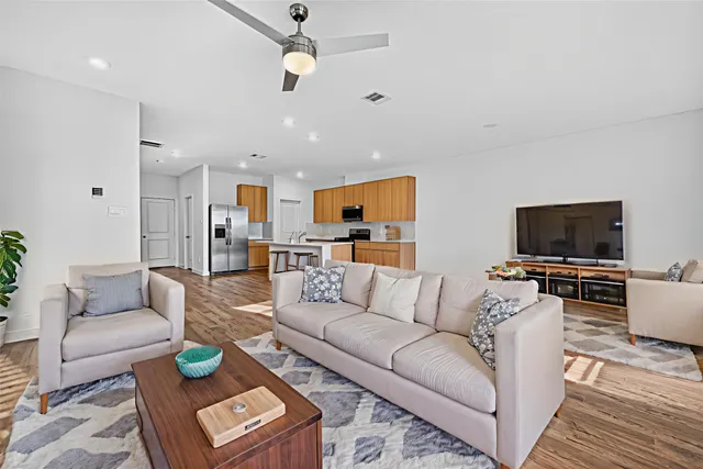 a kitchen with stainless steel appliances granite countertop a stove top oven a sink dishwasher a dining table and chairs with wooden floor