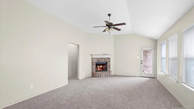 a view of a livingroom with a fireplace a ceiling fan and window