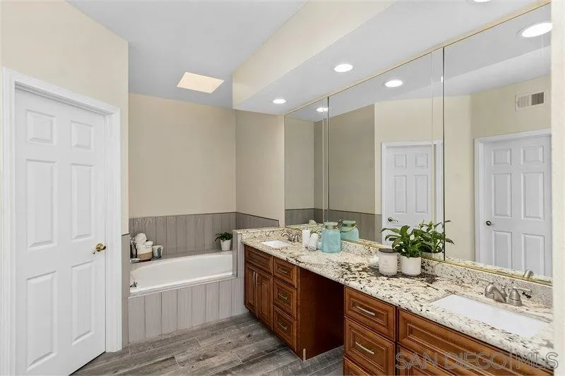 44113 Northgate Avenue Temecula, CA 92592 - Photo 21 of 30 a bathroom with a granite countertop double vanity sink and mirror with bathtub
