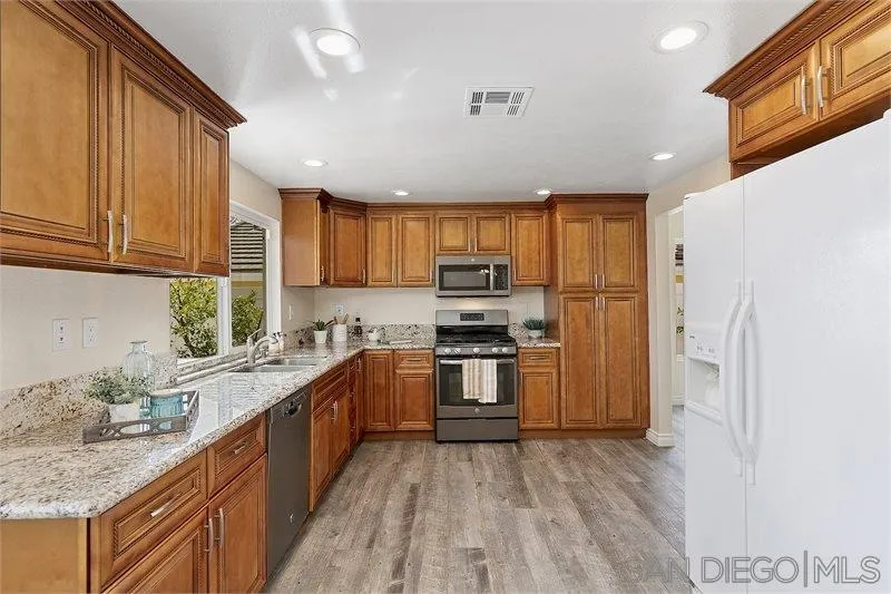 44113 Northgate Avenue Temecula, CA 92592 - Photo 7 of 30 a kitchen with stainless steel appliances granite countertop a refrigerator a sink dishwasher a stove with wooden cabinets and floor