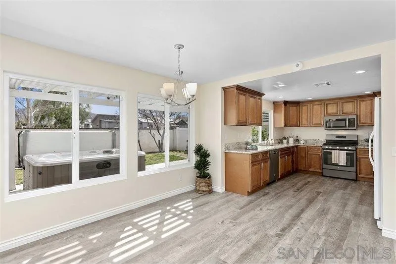 44113 Northgate Avenue Temecula, CA 92592 - Photo 9 of 30 a kitchen with stainless steel appliances kitchen island granite countertop a refrigerator a sink dishwasher a stove and a dining table with wooden floor