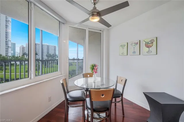 a dining room with furniture a large window and wooden floor
