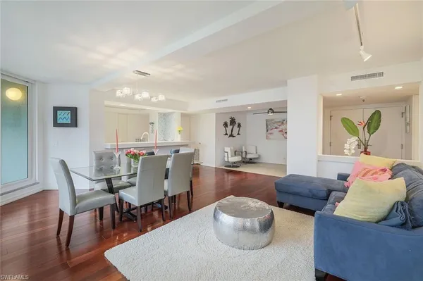 a living room with furniture and a dining table with wooden floor