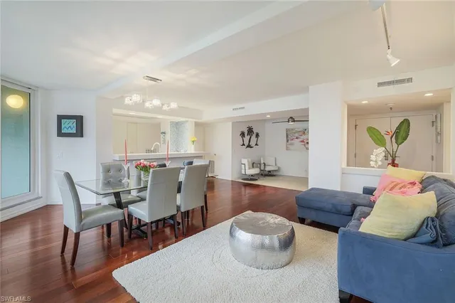 a living room with furniture and a dining table with wooden floor