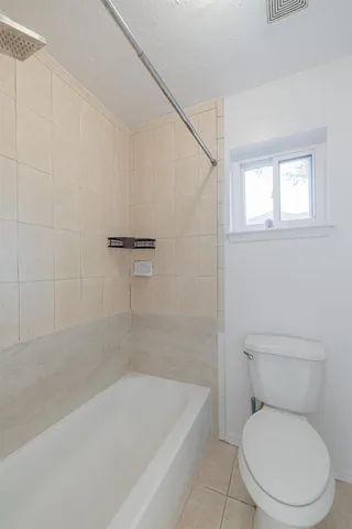 an empty room with chandelier fan and windows