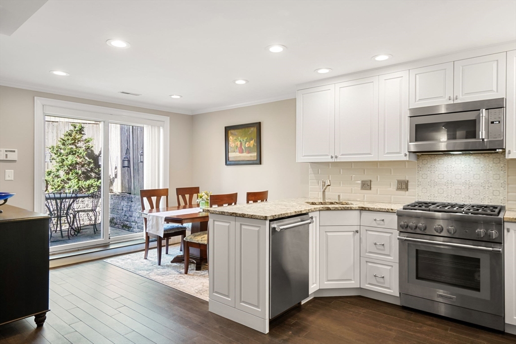 3 Harvard Place, Unit 1 Boston, MA 02129 - Photo 3 of 15 a kitchen with stainless steel appliances granite countertop a stove top oven a sink dishwasher a refrigerator and a dining table with wooden floor
