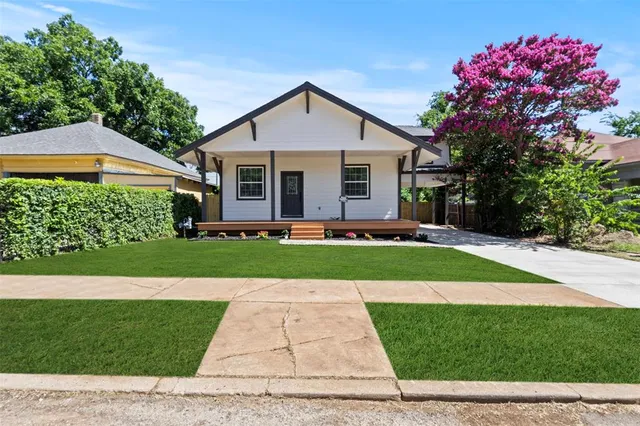 a front view of a house with a yard and potted plants